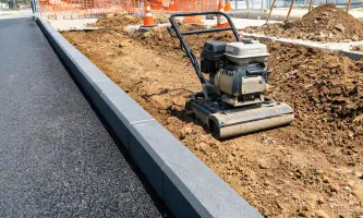 Plate compactor on trench backfill